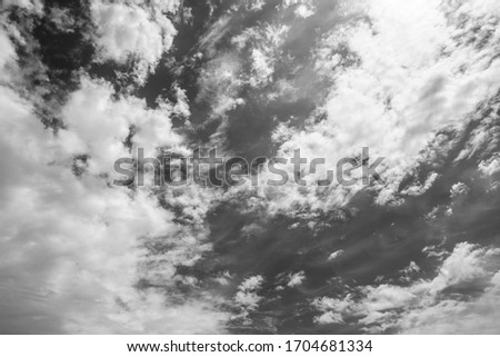 Beautiful sunny clear blue sky with many fluffy soft clouds and sunshine. Image filtered in black and white colors.
