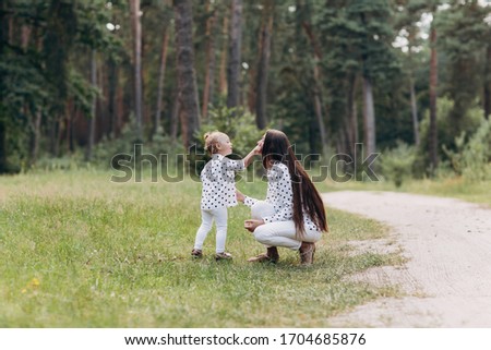 Beautiful Mother And her little daughter outdoors. Nature. Beauty Mum and her Child playing in Park together. Kissing and hugging happy family. Happy Mother's Day Joy. Mom and Baby