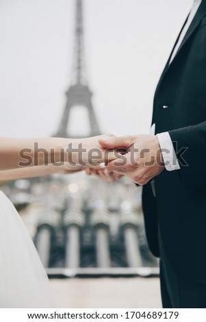 Bride and groom having a romantic marriage in Paris. Wedding couple on a background of Eiffel Tower in Paris. Romantic date, wedding ceremony in France. Bride in wedding dress. Wedding ring.