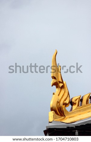 Gold naga statue on the roof of buddha temple in thailand