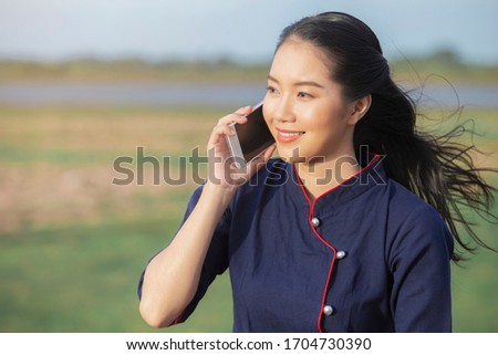 Beautiful young Asian woman happy while using smartphone outdoors at countryside of Thailand