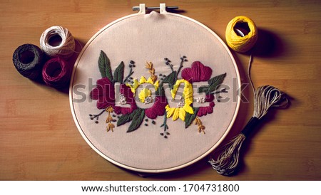 Embroidery work ( Love word written ) on fabric cloth and a wooden embroidery frame. Teen embroidery hobby