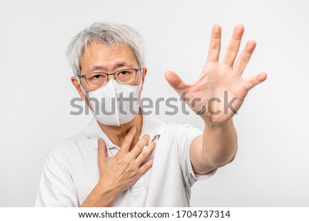 Old Asian man wearing N95 mask holding out his left hand with palm out stretch asking for help with his right hand touching his chest, health or medical concept