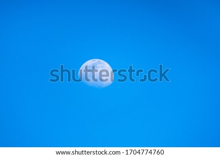 Blurred moon in the blue sky of a sunny day. Moon with the blue sky of day.