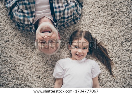 High angle top above photo of two people grandpa little granddaughter lying floor cozy fluffy carpet cheerful positive good mood stay home quarantine living room indoors