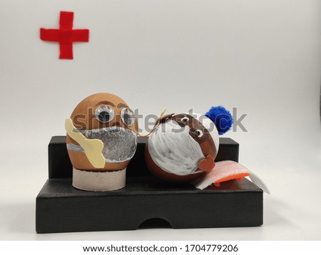 Installation, 2 easter eggs wearing medical masks, one in a white hat with a blue pompom, the other in a medical cap. they are sitting on a black sofa.