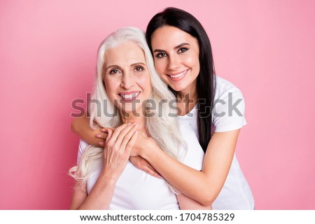 Photo of pretty old mother young daughter two ladies good mood hugging piggyback generation love comfort wear casual white t-shirts isolated pastel pink color background