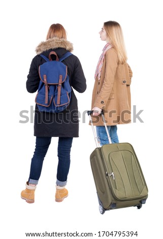Back view of two woman in winter jacket traveling with suitcas. Back view. Rear view people collection. backside view of person. Isolated over white background.