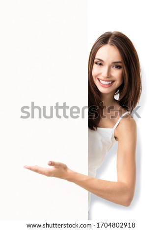 Portrait photo of brunette lovely woman showing blank signboard with copy space for some text or slogan, isolated over white background. Advertising, pr and marketing concept. 