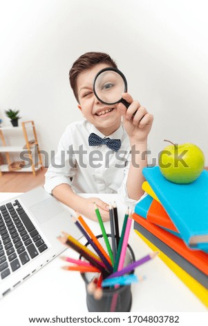 High angle playful boy with magnifying glass stack of books