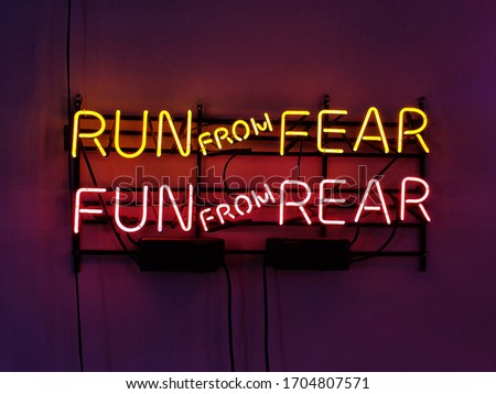 Neon sign phrase 'Run from fear, fun from rear.'
A glowing neon sign that is often used in shop interior design.