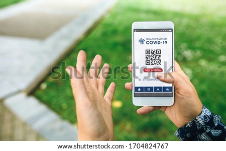 Mobile phone with not immune digital health passport for covid-19 held by an unrecognizable woman Royalty-Free Stock Photo #1704824767