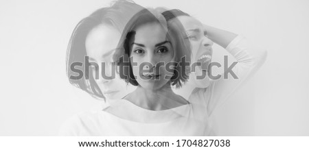 Multiple identities. Close-up photo of a young pretty brunette girl who is looking in the camera while internally suffering from a dissociative identity disorder. Double exposure. Royalty-Free Stock Photo #1704827038