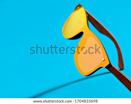 Minimal style closeup photography of  orange mirror sunglasses on blue background. Minimalist summer fashion or vacation concept. Eye protection.  Royalty-Free Stock Photo #1704833698