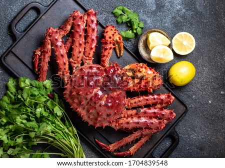 King Crab with lemon and cilantro on black background. Top view. Royalty-Free Stock Photo #1704839548