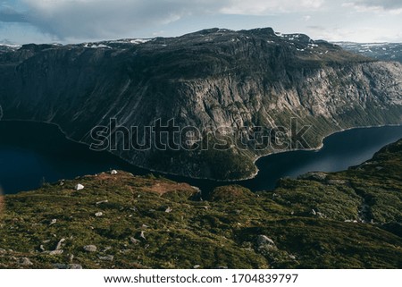 Norwegian fjords with mountainous rocky terrain, grass in summer at sunset. Blue river, beautiful landscape. Traveling in Europe, hiking.