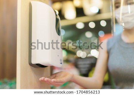 Woman Hands under the automatic alcohol dispenser to avoid the spread of coronavirus. Royalty-Free Stock Photo #1704856213