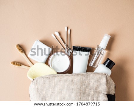 Travel cosmetic bag with the necessary means to care for women's skin. Cosmetics, dry shampoo, cotton buds, toothbrushes next a cosmetic bag on a beige background. top view
 Royalty-Free Stock Photo #1704879715