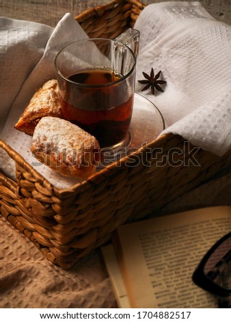 Tea and sweet cookies in a wicker tray on white wooden background. Open Book near the afteroon tea