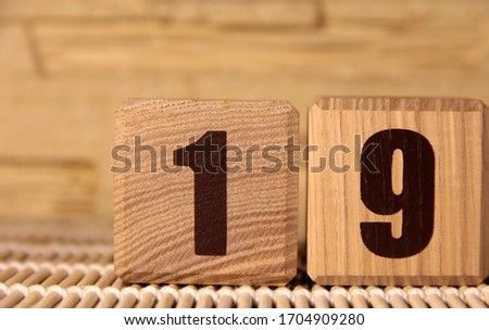 The number nineteen on a wooden cube on a beige background. Cube on a bamboo Mat.
