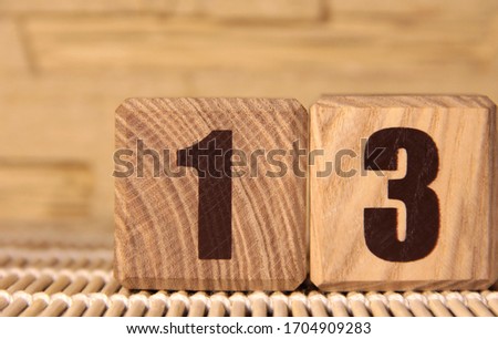 The number thirteen on a wooden cube on a beige background. Cube on a bamboo Mat.