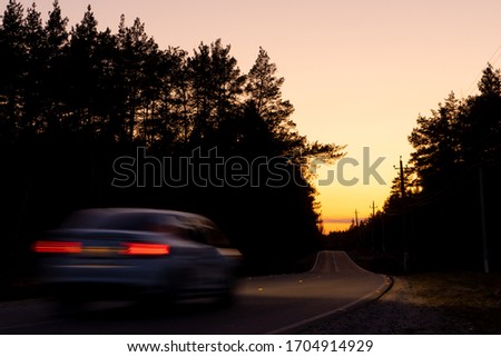 a car is driving along an empty asphalt road through a forest, road car travel adventure.

