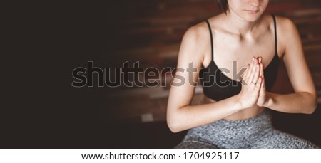 Young woman practicing yoga with namaste, working out, wearing sportswear, indoor. banner with copyspace