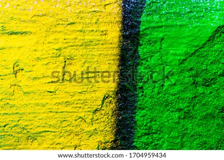 Fragment of colorful graffiti painted on a concrete wall. Bright yellow and green abstract background for design.