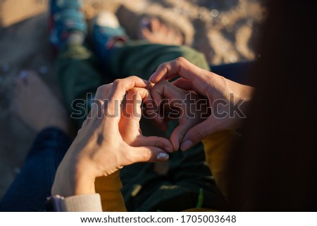 close up of mother's and child's hands making a heart sign, make love not war