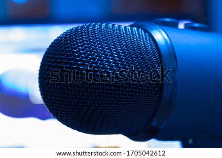 Concept of podcast or broadcasting radio. Pro condenser mic with blurry background with laptop. Blue light