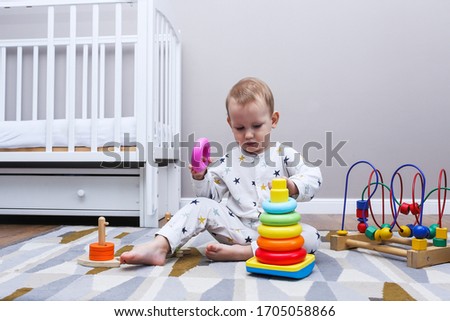 baby boy plays with educational toy. toddler play with a wooden toys at home. Toddler play with a color educational toy. Child play at the table in the baby room. Child development. 