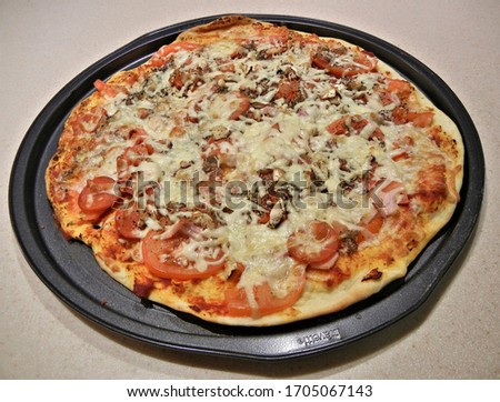 baked pizza on a black plate under a thick layer of cheese