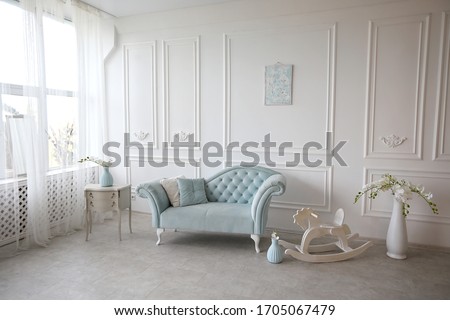 The interior is decorated in pastel blue tones with a vintage sofa.White walls with plaster stucco.