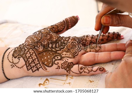 Hand mehndi designs are being prepared and ready for the function Royalty-Free Stock Photo #1705068127