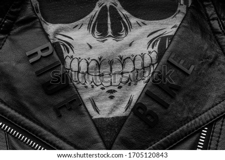 closeup to ride bike lettering over biker leather jacket and skull kerchief. motorcycle style, black and white photography