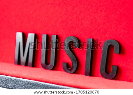 Closeup to a MUSIC black lettering word over a red background. Music lover concept
