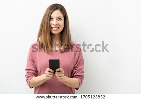 Portrait of a pretty brunette holding a smartphone and making eye contact in a studio