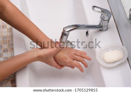 The girl brought the burn place under a stream of water for first aid Royalty-Free Stock Photo #1705129855