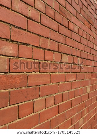 Photo with perspective of an old red brick wall with uneven brickwork, at an angle close to the wall