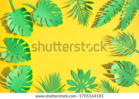Green paper cutout tropical leaves on yellow background. Handmade and craft for banner. 