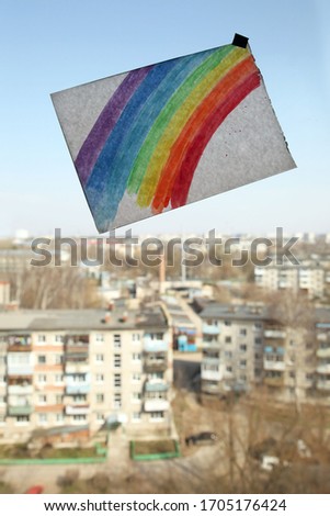 a picture of a rainbow is pasted on a window in a room on a high floor