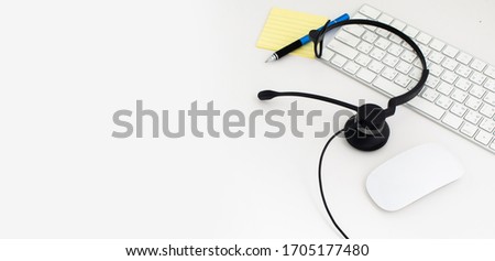 VOIP headset and paper note on laptop computer keyboard. Communication support for callcenter and customer service Helpdesk. Isolated on white background. top view flat lay background. Space for text