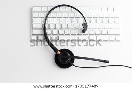 VOIP headset on laptop computer keyboard. Communication support for callcenter and customer service Helpdesk. Isolated on white background. top view flat lay background. Space for text design.
