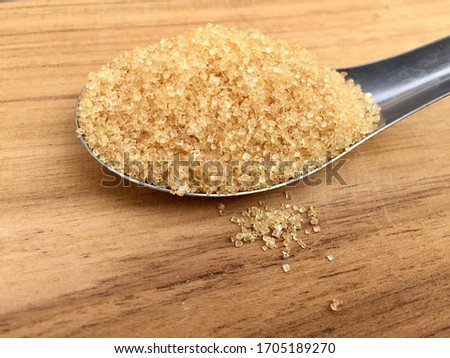 Spoon with brown sugar on a wood background.