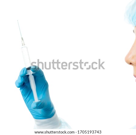 Laboratory Assistant, Doctor. A medic in a disposable medical gown, mask, glasses, hat, gloves holds a syringe. close-up isolated