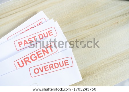 Debt letters that are collected on past overdue bills and final announcements on the table. Red writing to represent the struggle against economic unemployment. Royalty-Free Stock Photo #1705243750
