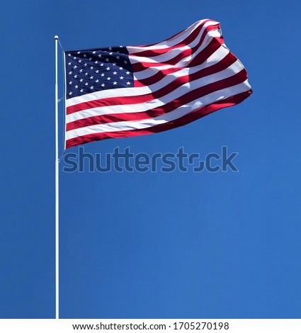 Waving American flag on pole isolated on blue sky background including clipping path