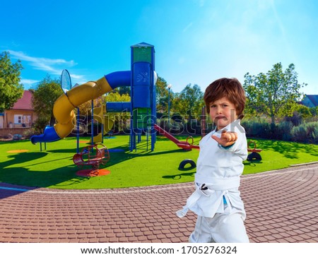 Handsome boy in a white kimono practices judo. Cosy children 's playground with a variety of multicolored attractions. The concept of physical and mental development of children