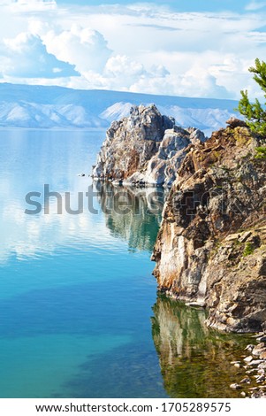 Magnificent summer landscape with Baikal Lake on a sunny day. Two famous rocks of Olkhon Island - Shamanka and Hero Rocks are reflected in calm water. Summer travel, natural background