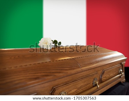 funeral and mourning concept - white rose flower on wooden coffin over flag of italy on background